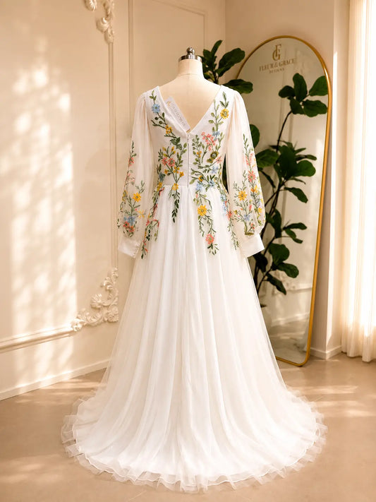 Back view of a white A-line wedding dress with colorful floral embroidery, illusion long sleeves, and a V-back on tulle.