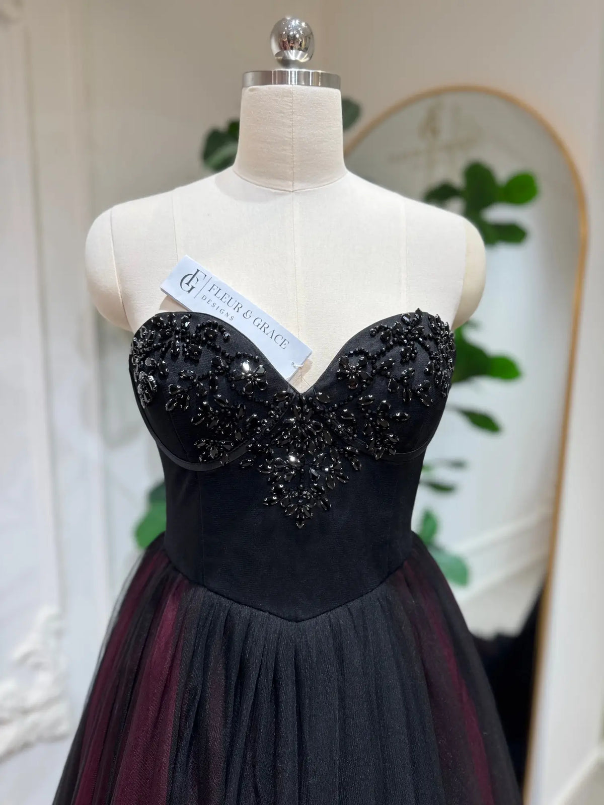 Black and burgundy tulle wedding dress with a hand-beaded sweetheart corset bodice on a mannequin.