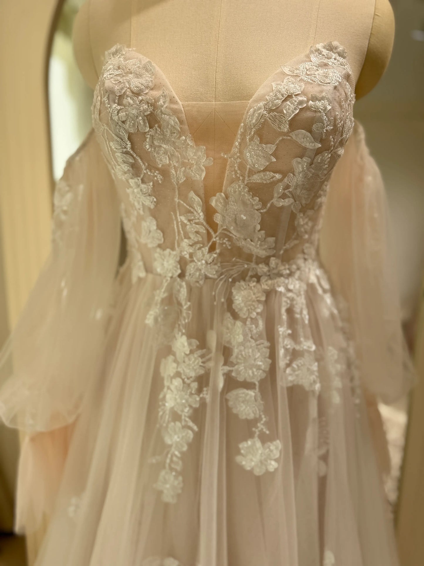 Aure Gown by Fleur&Grace Designs – romantic floral embroidered wedding dress with plunging neckline, removable long sleeves, soft tulle skirt, and A-line silhouette, perfect for whimsical weddings and elopements.