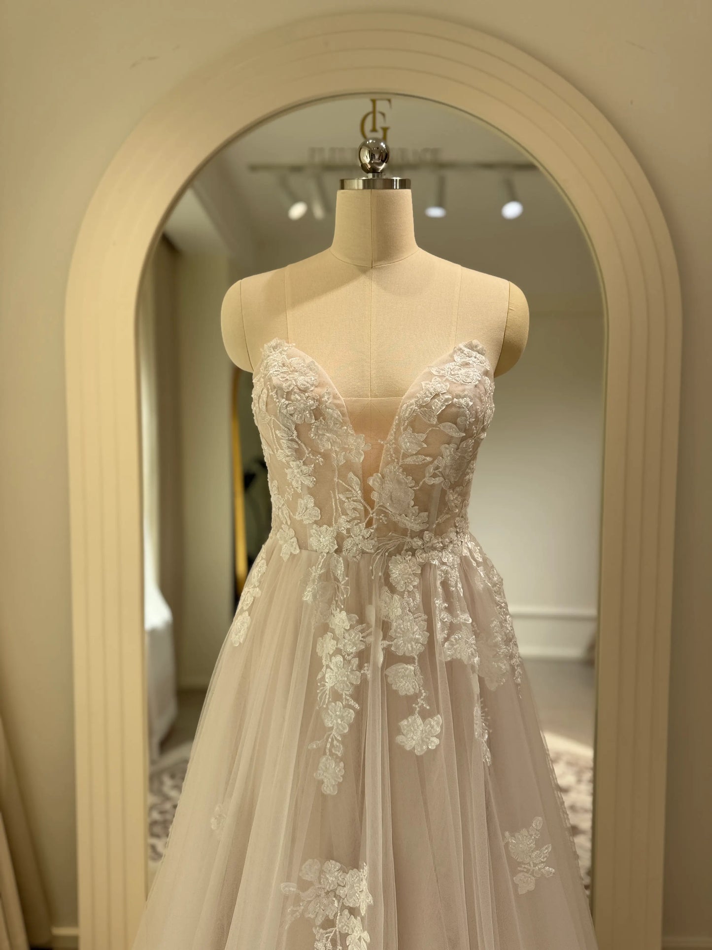 Aure Gown by Fleur&Grace Designs – romantic floral embroidered wedding dress with plunging neckline, removable long sleeves, soft tulle skirt, and A-line silhouette, perfect for whimsical weddings and elopements.