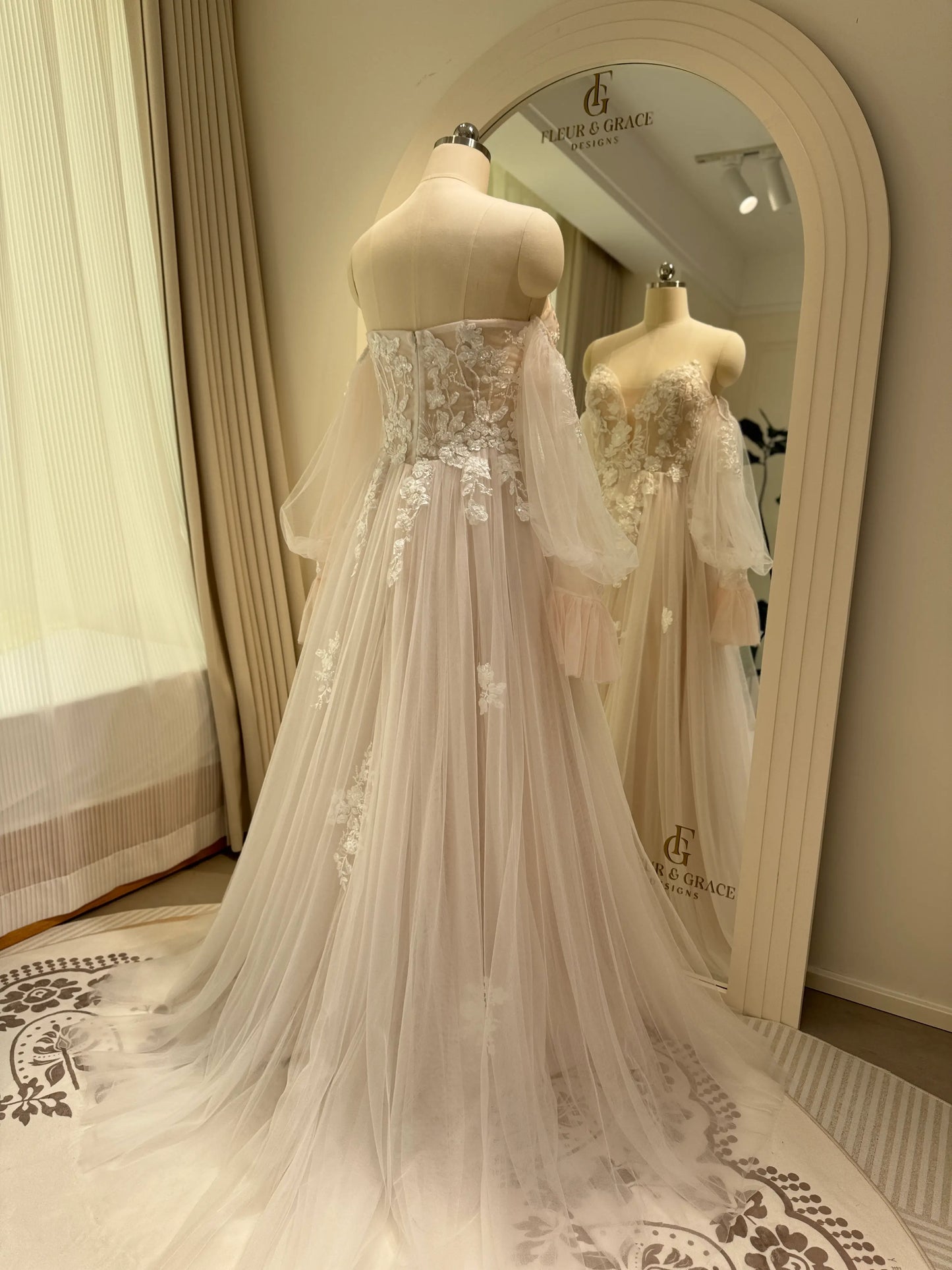 Aure Gown by Fleur&Grace Designs – romantic floral embroidered wedding dress with plunging neckline, removable long sleeves, soft tulle skirt, and A-line silhouette, perfect for whimsical weddings and elopements.