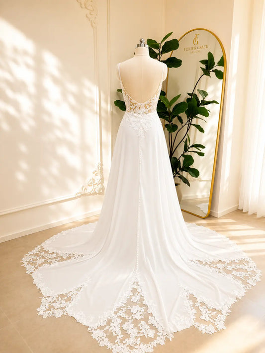 Back view of a white chiffon A-line wedding dress with a low open back, lace bodice, and lace-trimmed chapel train.