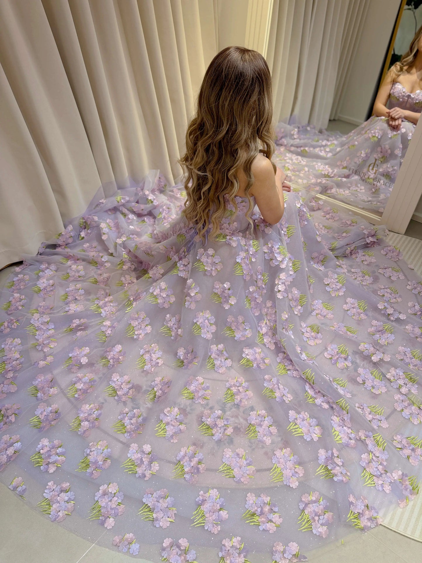 Model wearing the Lavender Elysia Gown FG016 by Fleur&Grace Designs – floor-length lavender dress with 3D hydrangea floral lace, sparkly mesh lining, and lace-up back, perfect for prom, garden weddings, formal evenings, and whimsical photography.