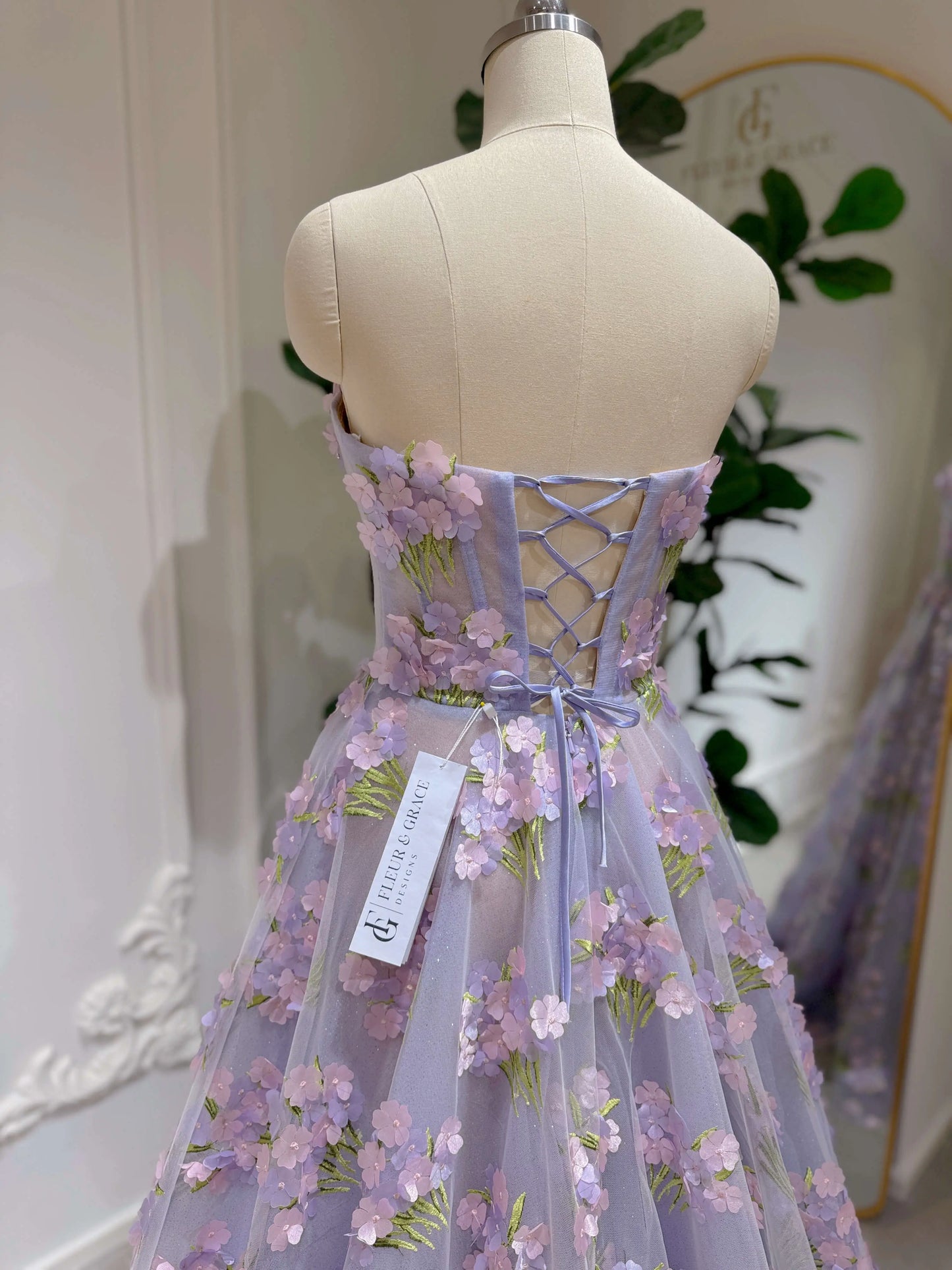 Model wearing the Lavender Elysia Gown FG016 by Fleur&Grace Designs – floor-length lavender dress with 3D hydrangea floral lace, sparkly mesh lining, and lace-up back, perfect for prom, garden weddings, formal evenings, and whimsical photography.