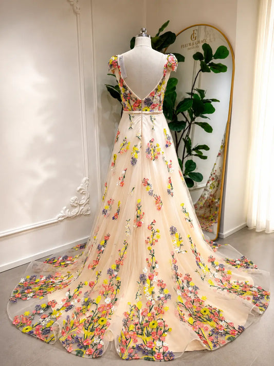Champagne A-line wedding dress with colorful floral embroidery, cap sleeves, and a low V-back on a tulle chapel train.