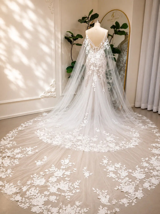 Nola mermaid wedding dress with floral lace, nude lining, and a dramatic detachable tulle cape with lace trim.