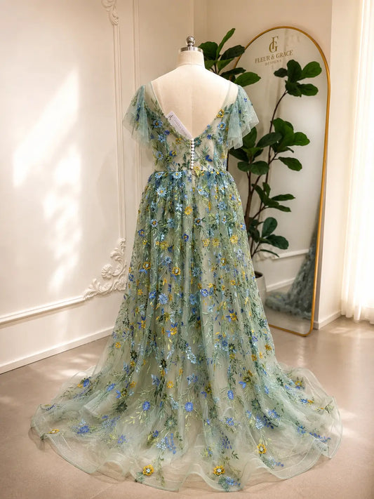 Sage green tulle gown with blue and yellow floral embroidery, angel sleeves, and a button-back corset bodice.