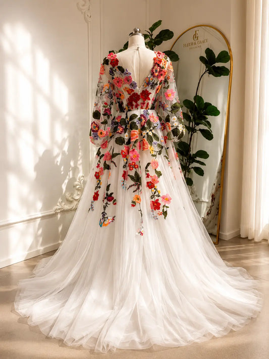 Suri wedding dress with colorful floral embroidery, sheer bishop sleeves, and a flowing A-line tulle skirt.