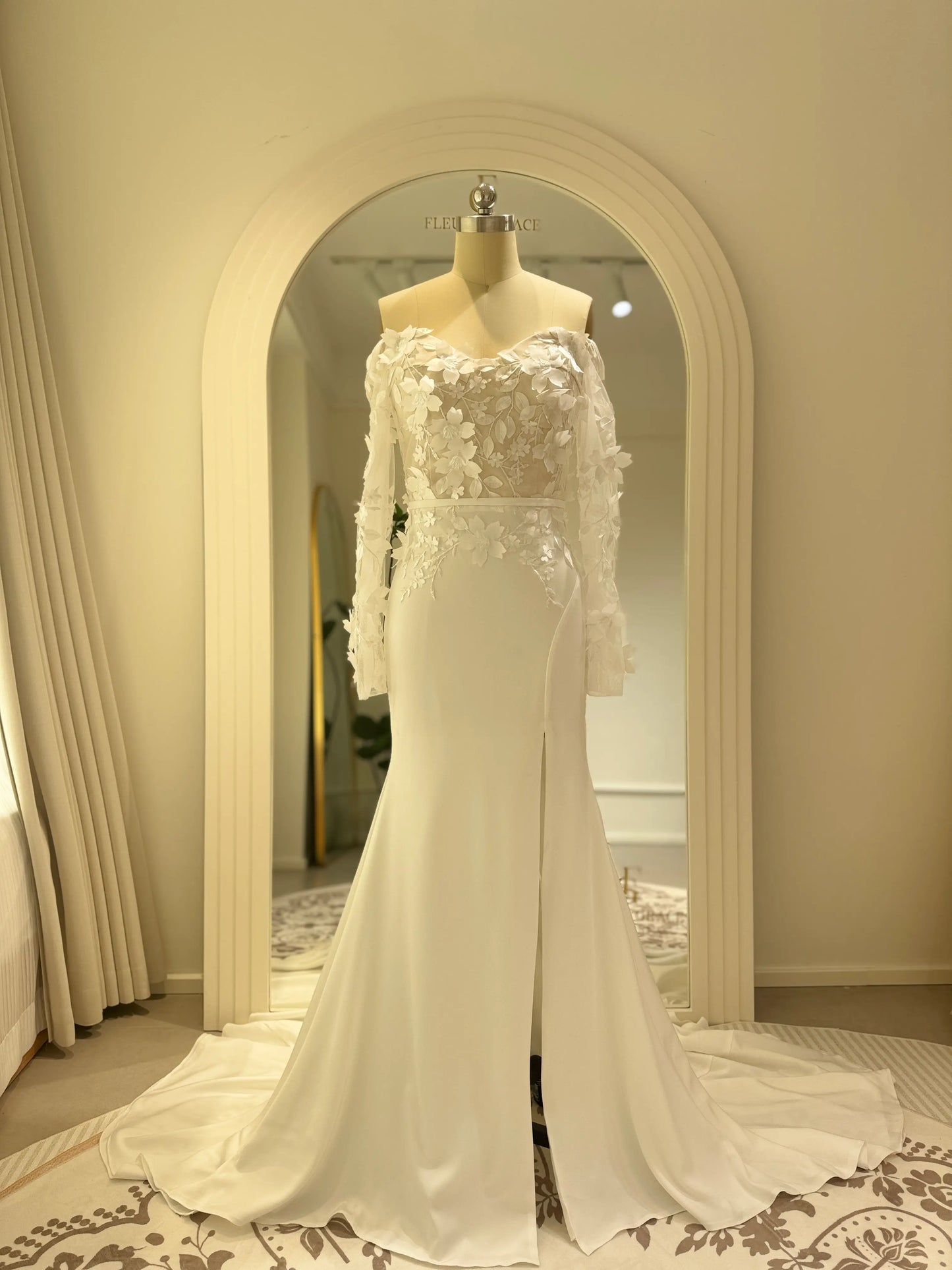 Zoe Gown by Fleur&Grace – minimalist matte crepe wedding dress with 3D floral lace bodice, long off-the-shoulder sleeves, side slit, and train, perfect for modern and romantic weddings.