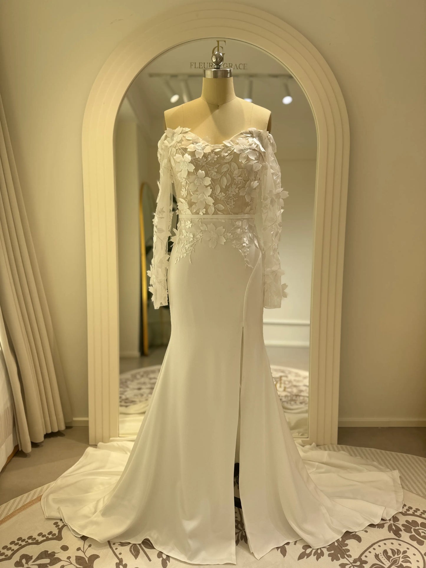 Zoe Gown by Fleur&Grace – minimalist matte crepe wedding dress with 3D floral lace bodice, long off-the-shoulder sleeves, side slit, and train, perfect for modern and romantic weddings.
