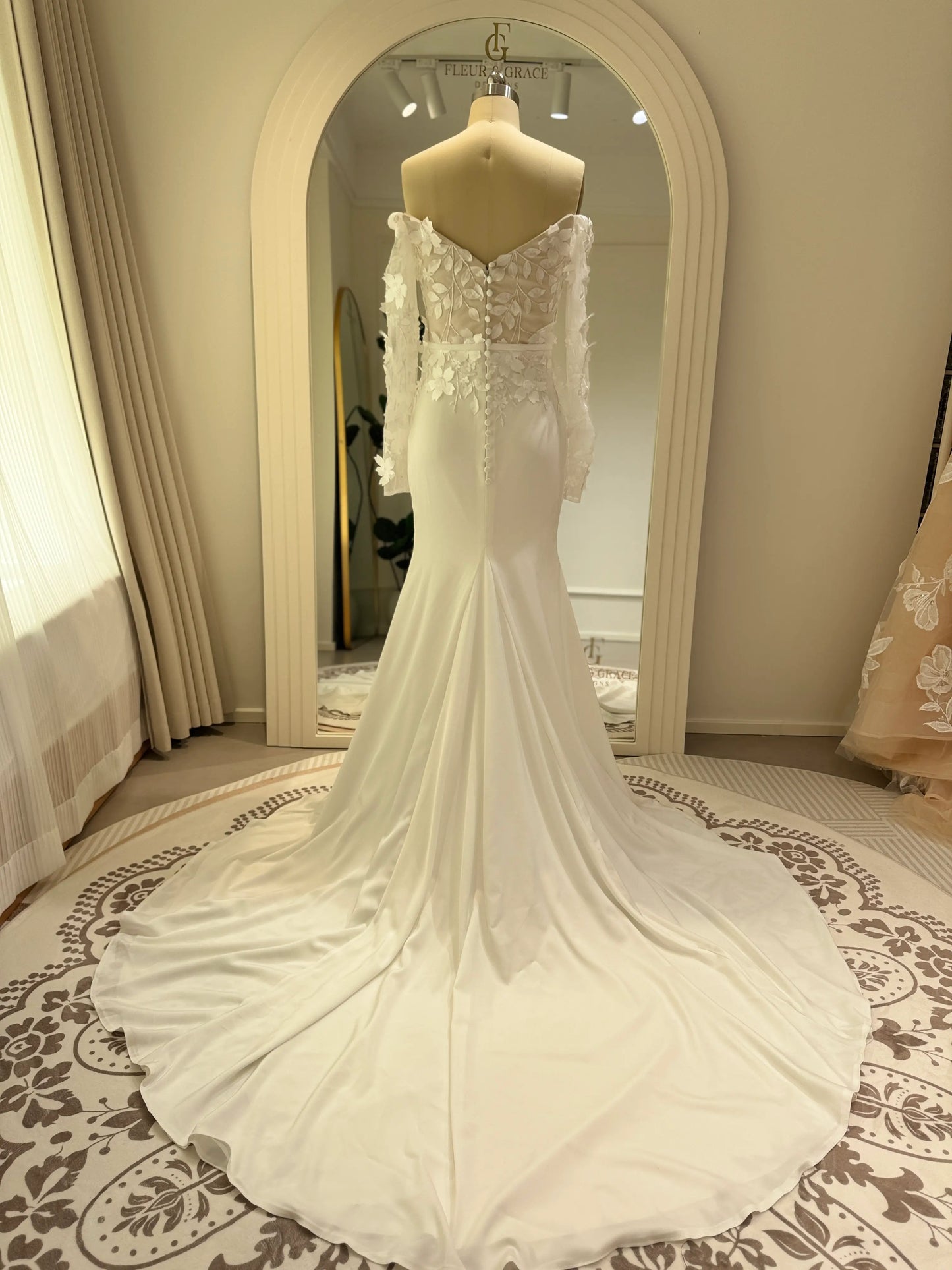 Zoe Gown by Fleur&Grace – minimalist matte crepe wedding dress with 3D floral lace bodice, long off-the-shoulder sleeves, side slit, and train, perfect for modern and romantic weddings.