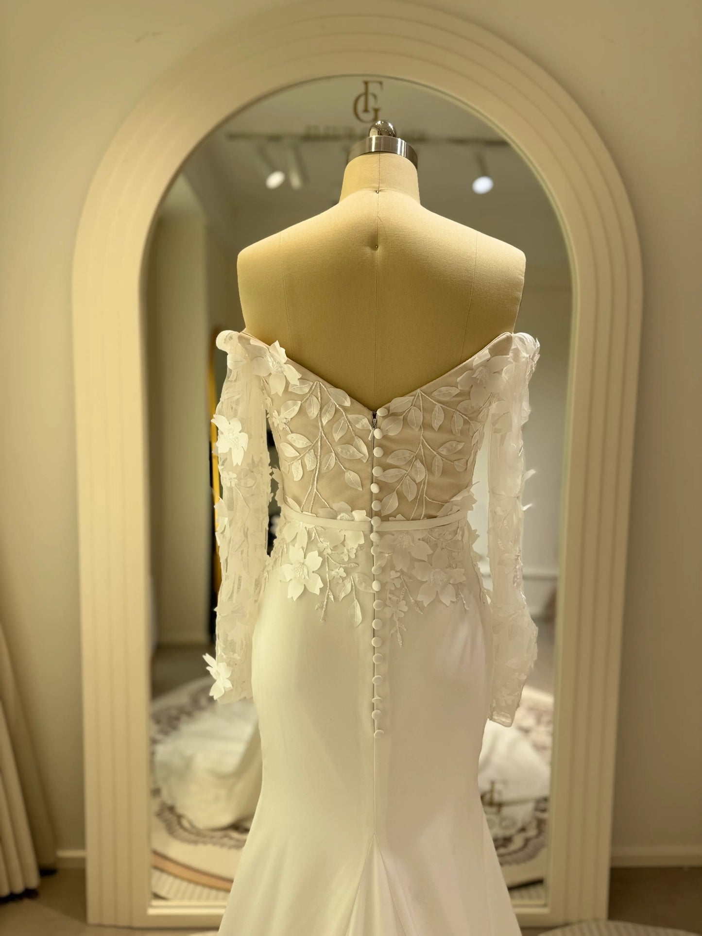 Zoe Gown by Fleur&Grace – minimalist matte crepe wedding dress with 3D floral lace bodice, long off-the-shoulder sleeves, side slit, and train, perfect for modern and romantic weddings.