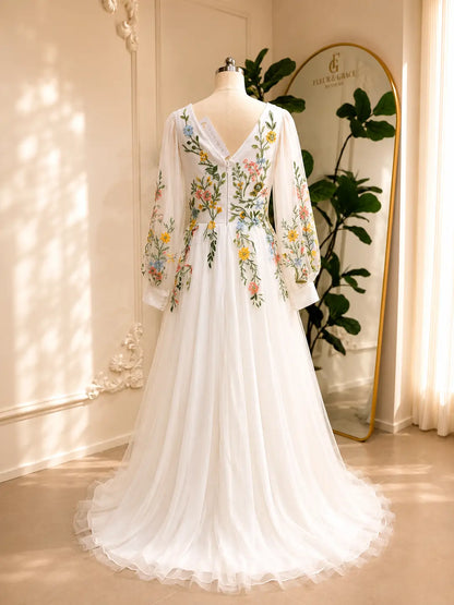 Back view of a white A-line wedding dress with colorful floral embroidery, illusion long sleeves, and a V-back on tulle.