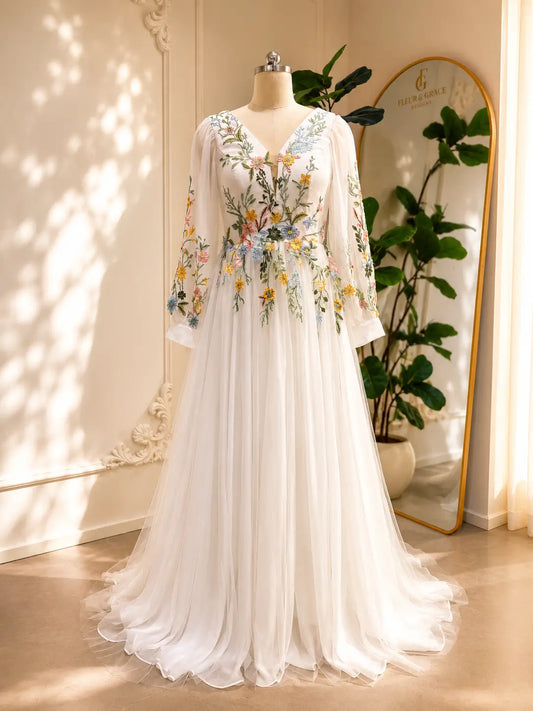 White A-line wedding dress with long illusion sleeves and colorful botanical floral embroidery on tulle.