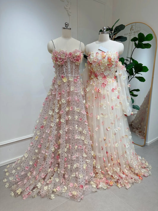 Two mannequins wearing pink and yellow 3D floral lace gowns with sweetheart necklines and flowing court trains.
