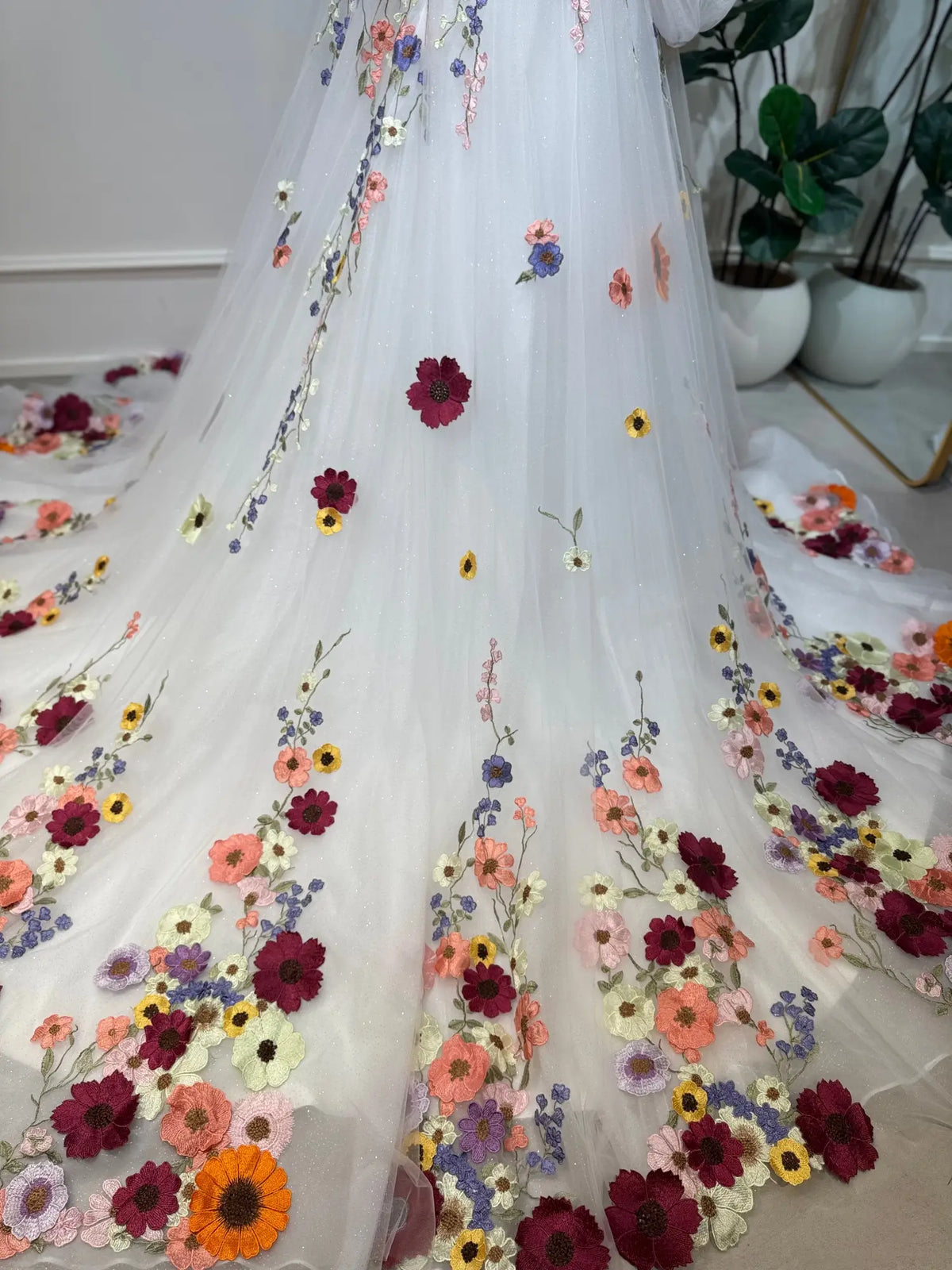 White sparkle tulle wedding dress with colorful 3D floral embroidery and botanical appliqués on an A-line skirt.