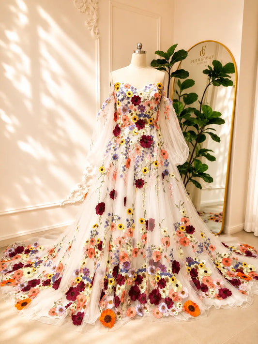 Alina A-line wedding dress featuring colorful 3D floral appliqués, off-the-shoulder neckline, and airy illusion sleeves.