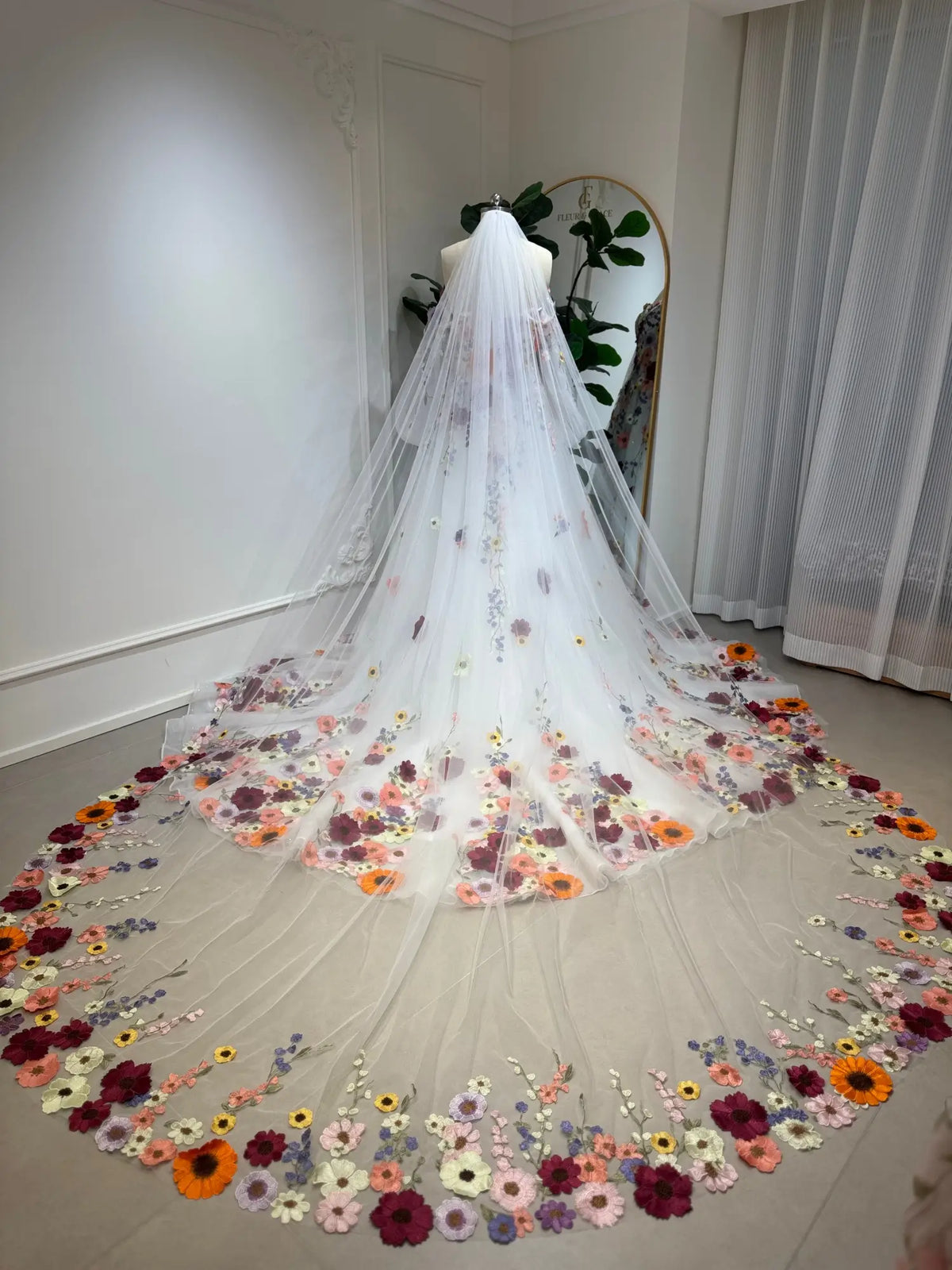 Cathedral-length white tulle wedding veil featuring vibrant, handcrafted 3D floral embroidery along the sweeping hem.