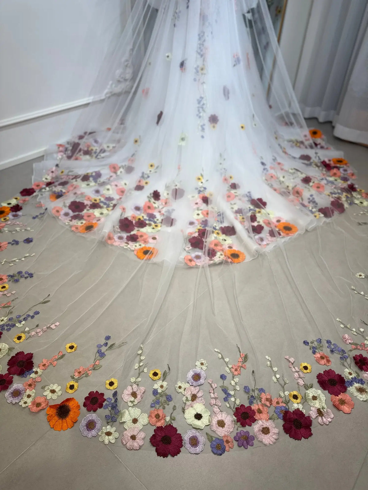 Cathedral-length white tulle wedding veil featuring vibrant, handcrafted 3D floral embroidery along the sweeping hem.