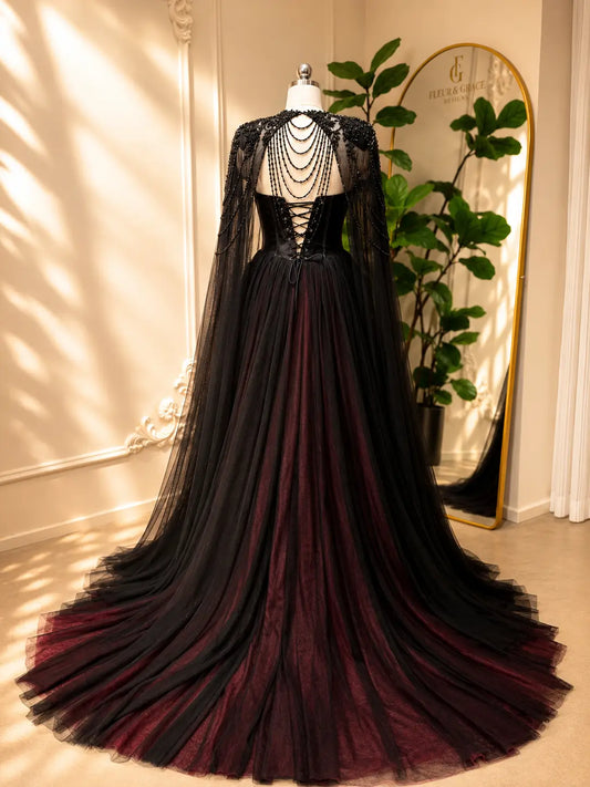 Black and burgundy A-line wedding dress with a beaded illusion cape, corset back, and dramatic tulle train.