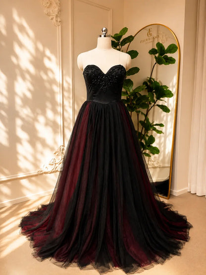 Black and burgundy A-line wedding dress with a beaded sweetheart corset bodice and layered tulle skirt on a mannequin.