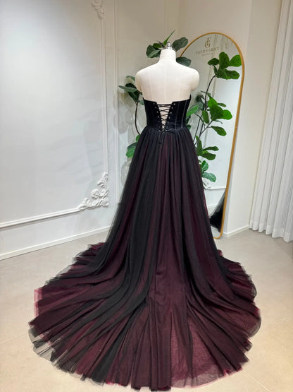 Black and burgundy tulle wedding dress with a strapless corset bodice and lace-up back on a mannequin.