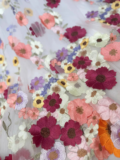 Off-white tulle fabric featuring vibrant, multicolored floral embroidery appliqués for a whimsical wedding gown.