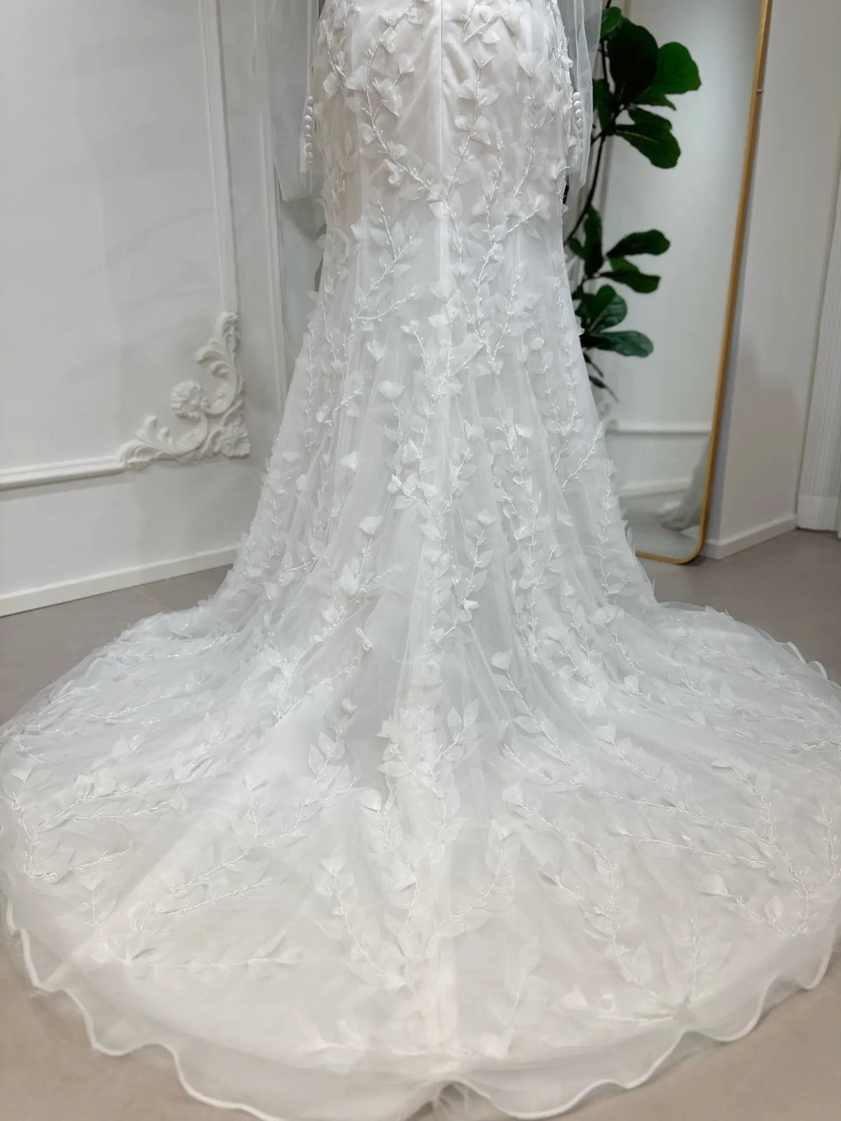 White mermaid wedding dress with 3D floral appliqués, intricate hand-sewn beading, and a flowing tulle train.