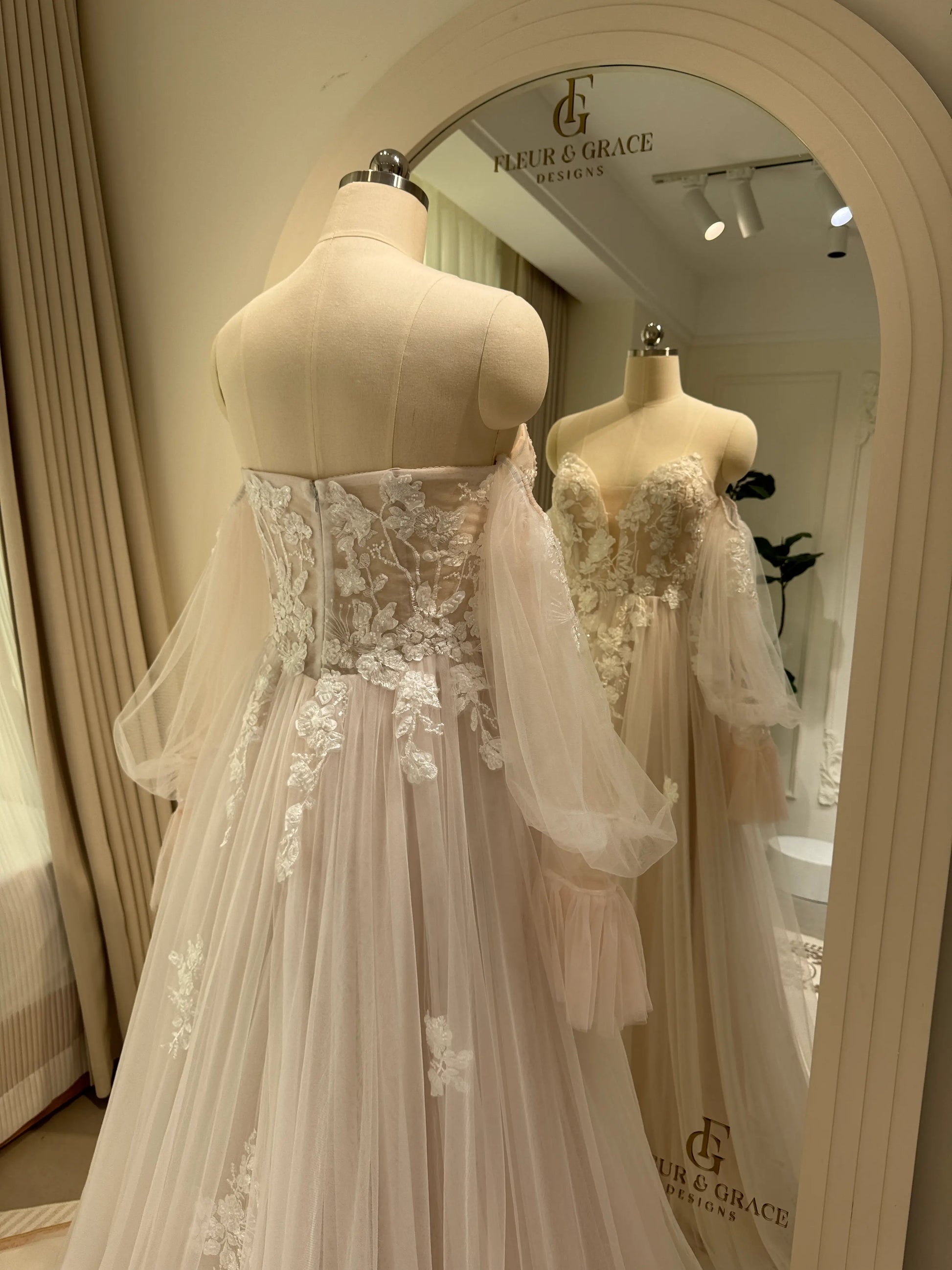 Aure Gown by Fleur&Grace Designs – romantic floral embroidered wedding dress with plunging neckline, removable long sleeves, soft tulle skirt, and A-line silhouette, perfect for whimsical weddings and elopements.