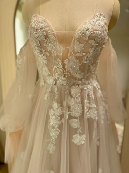 Ivory tulle wedding gown with floral embroidery, plunging illusion neckline, and removable sheer puff sleeves.