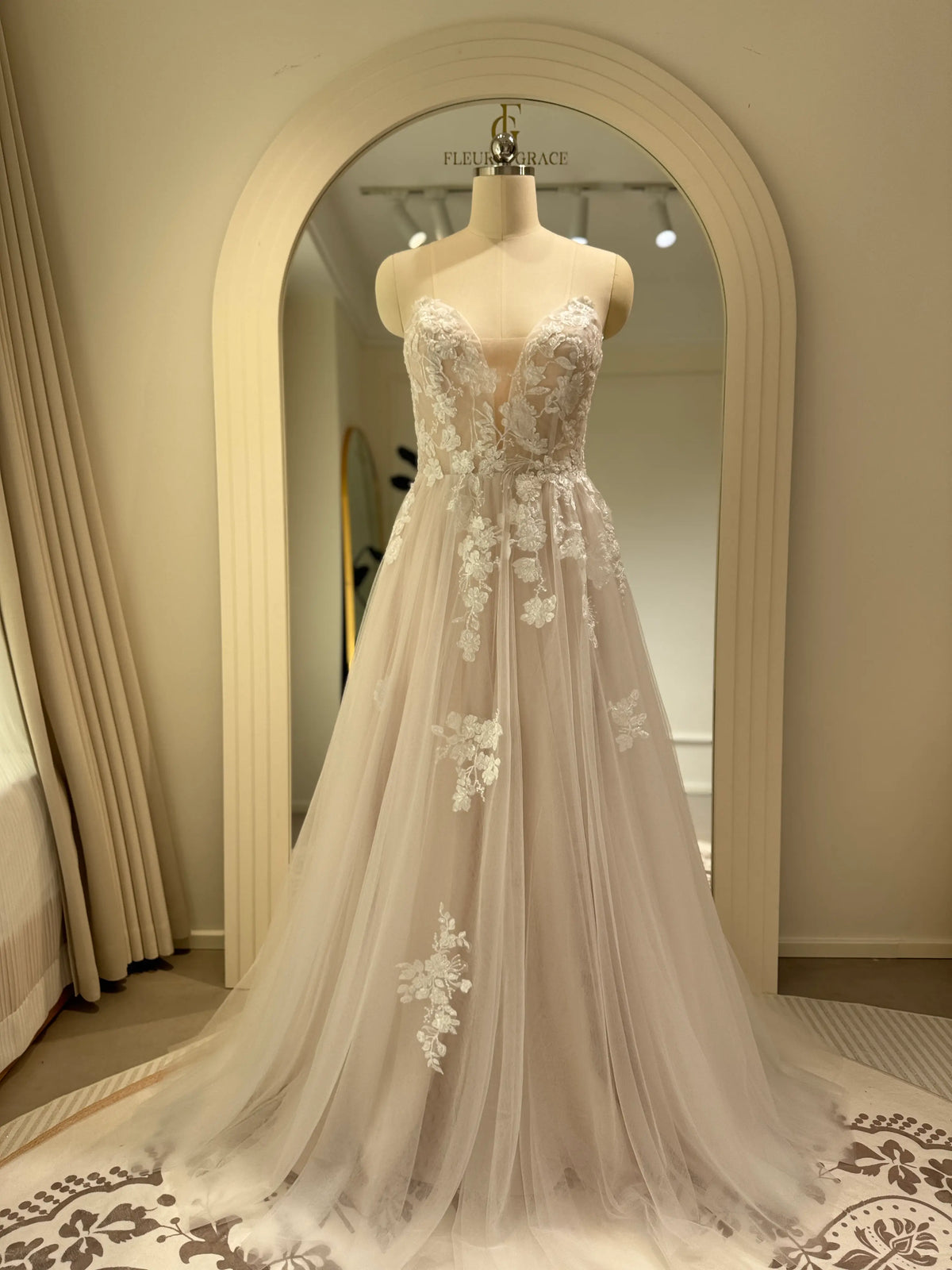 Ivory A-line wedding gown with floral embroidery on tulle, featuring a plunging illusion V-neckline on a structured bodice.