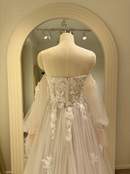 Ivory tulle wedding gown with floral embroidery, structured bodice, and removable sheer puff sleeves on a mannequin.