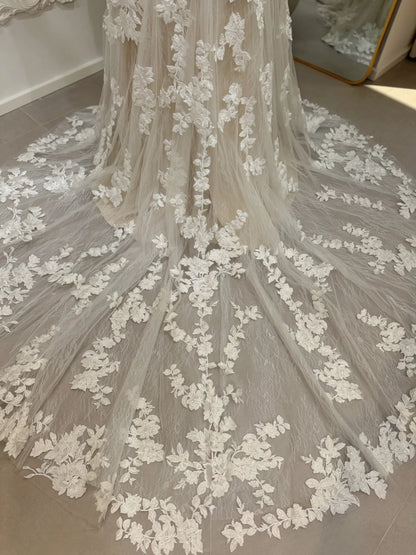 Mermaid wedding dress train with intricate white floral embroidery, lace detailing, and subtle sequin glitter accents.