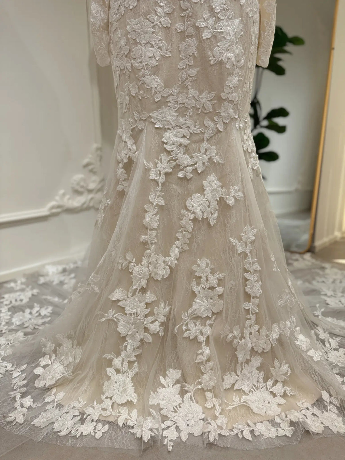 Ivory mermaid wedding dress featuring intricate white floral embroidery, sparkly sequin accents, and a lace-detailed train.