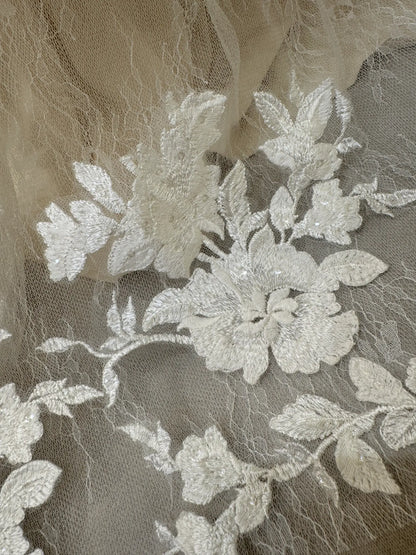 White floral embroidery with subtle sequins on delicate sheer tulle fabric for a wedding gown.