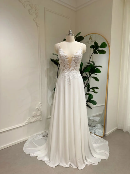 A-line chiffon wedding dress with a deep V-neck, floral lace bodice, and a flowing skirt on a mannequin.