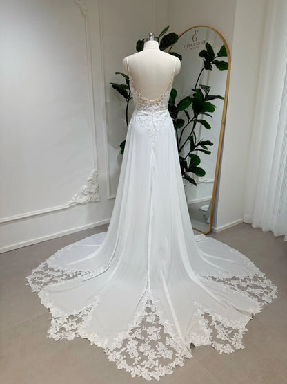 White chiffon A-line wedding dress with an open back, floral lace bodice, and a lace-trimmed chapel train.