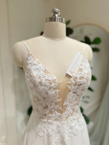 White chiffon wedding dress with a deep V-neckline, delicate floral lace appliqué bodice, and thin spaghetti straps.