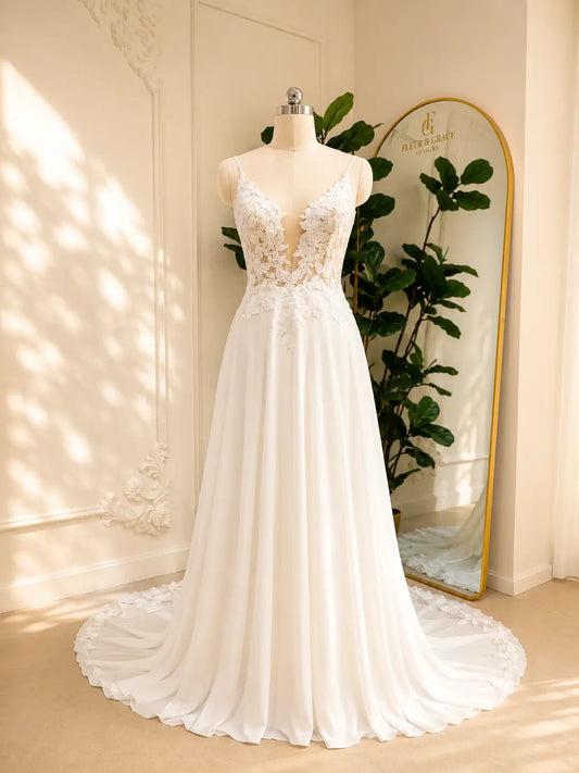 White chiffon A-line wedding dress with a deep V-neck, floral lace bodice, and lace-trimmed chapel train on a mannequin.