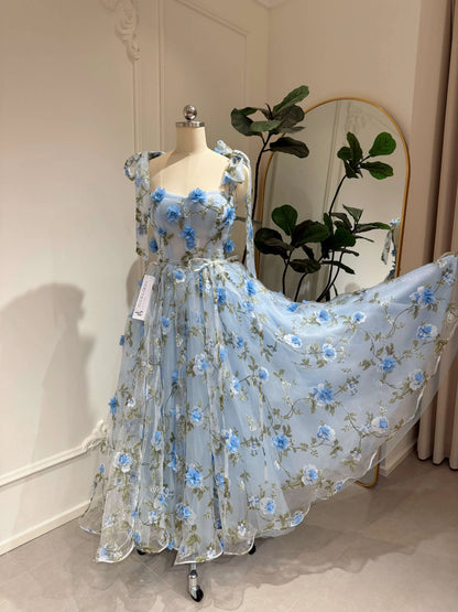 Blue ankle-length gown with 3D floral organza, green leaf prints, sweetheart neckline, and sparkly mesh overlay.