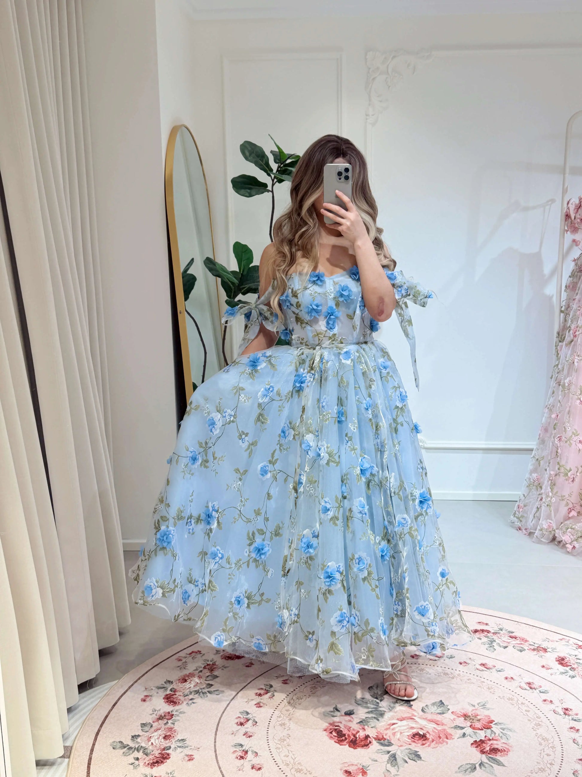 Blue ankle-length gown with 3D floral organza, green leaf prints, sweetheart neckline, and tie-shoulder straps.