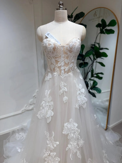Strapless A-line wedding dress with a sweetheart neckline, sheer bodice, and white 3D floral lace on layered tulle.