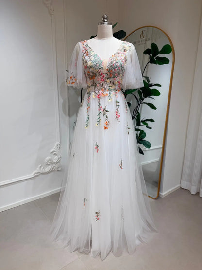 White A-line wedding dress with floral embroidery, V-neckline, and flutter sleeves on a mannequin.