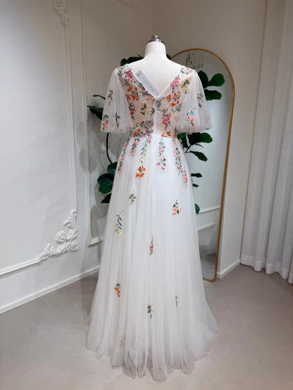 White A-line wedding dress with flutter sleeves, V-neck, and colorful floral embroidery on tulle fabric.