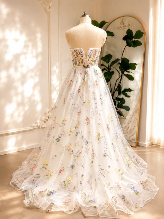 A-line wedding dress with a floral embroidered corset bodice and airy tulle skirt featuring colorful pastel blooms.