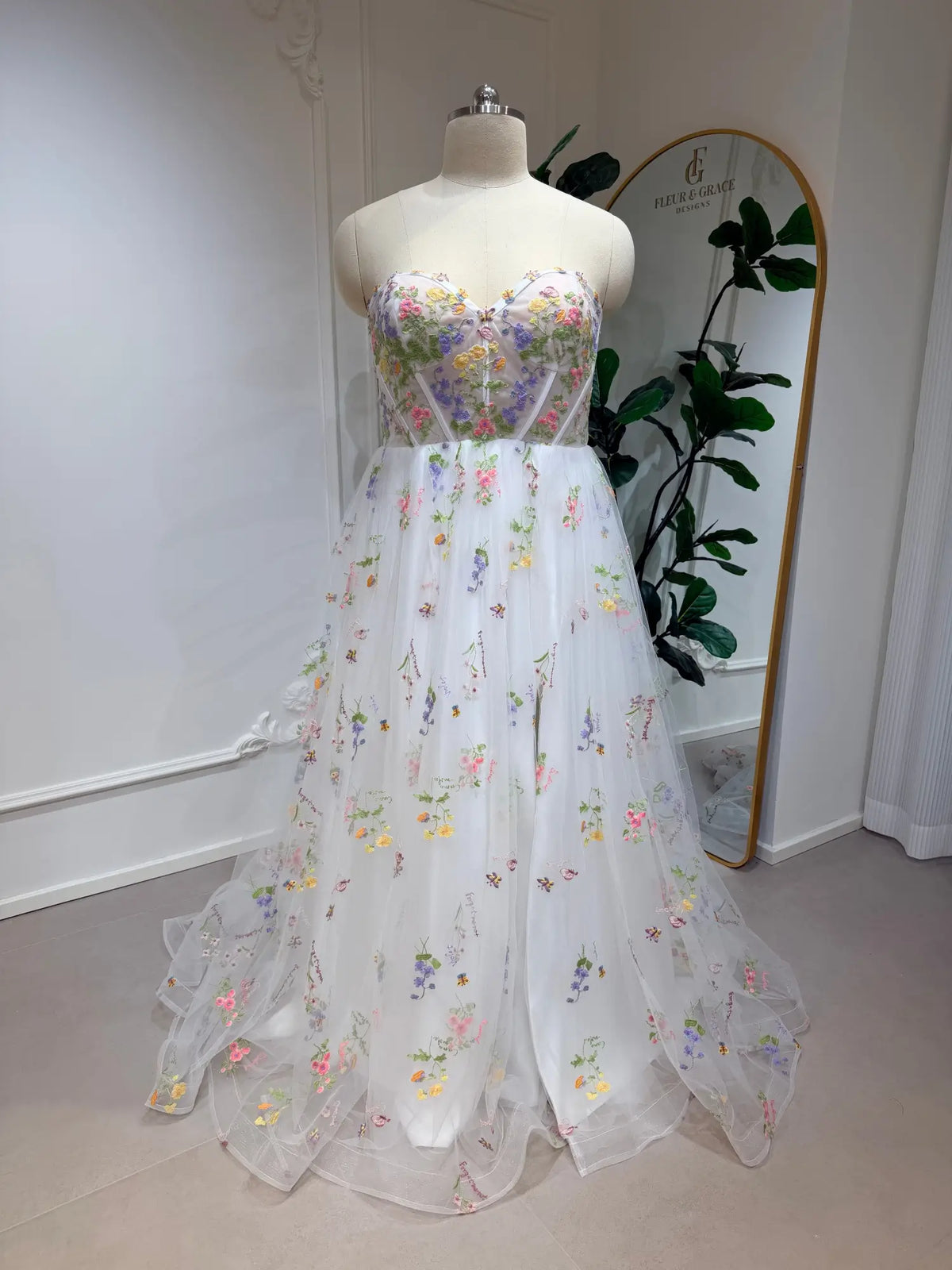 A-line wedding dress with a corset bodice and tulle skirt featuring colorful pastel floral embroidery.