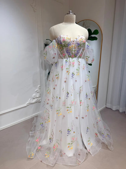 A-line wedding dress with pastel floral embroidery, corset bodice, and sheer detachable puff sleeves on tulle.