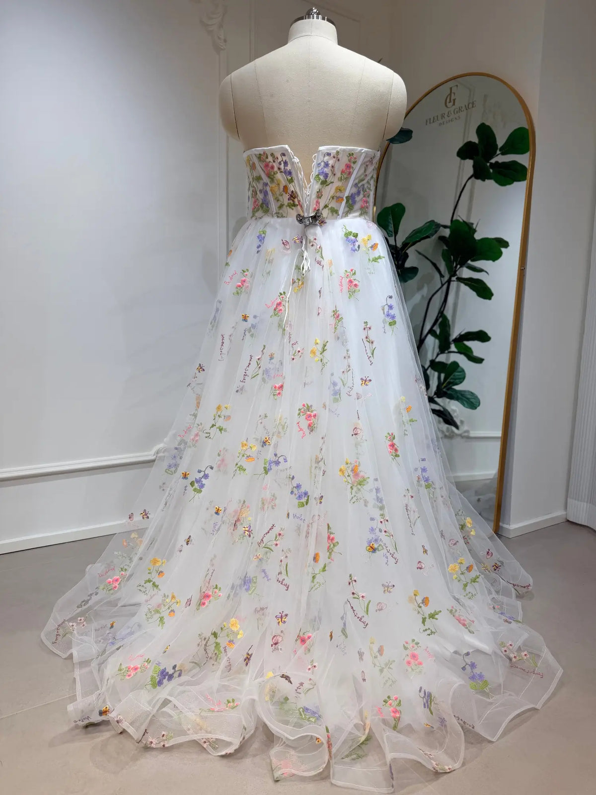 Strapless A-line wedding dress with a corset bodice and colorful floral embroidery on layered white tulle.