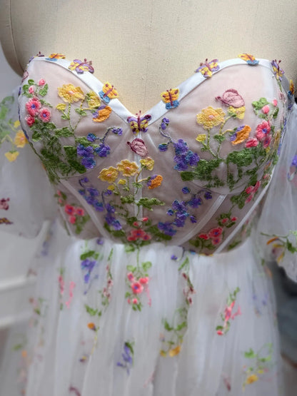 Corset bodice wedding dress with colorful floral embroidery and sheer tulle on a mannequin.