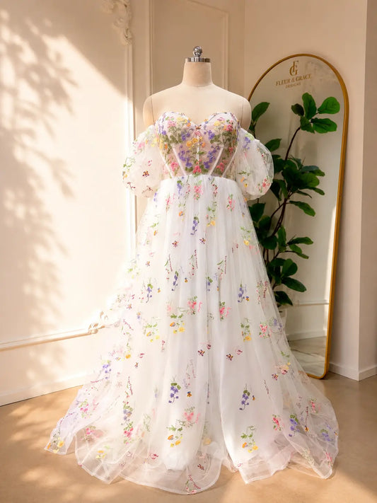 A-line wedding dress with pastel floral embroidery, corset bodice, and detachable sheer puff sleeves on tulle.